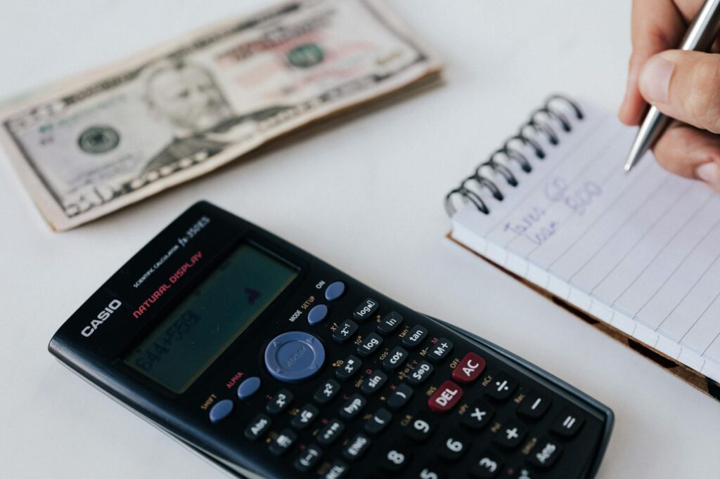 Monthly bills, a budget notebook, and money set aside for emergencies