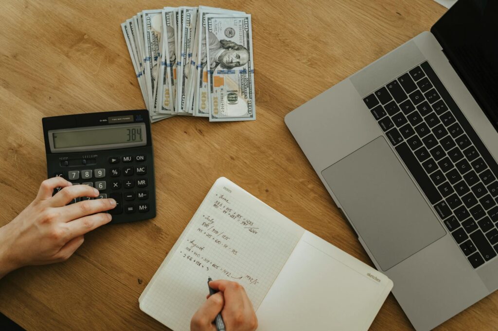 A person reviewing a financial website on a laptop while checking notes