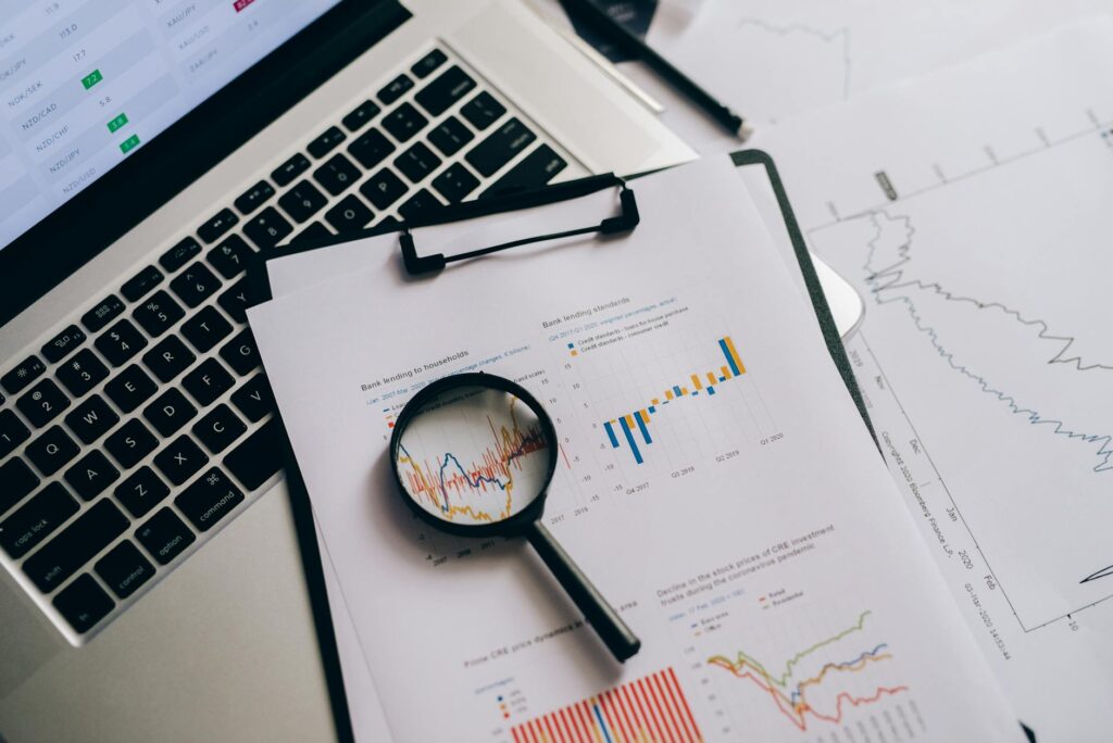 Laptop and printed fund documents laid out for a cost comparison