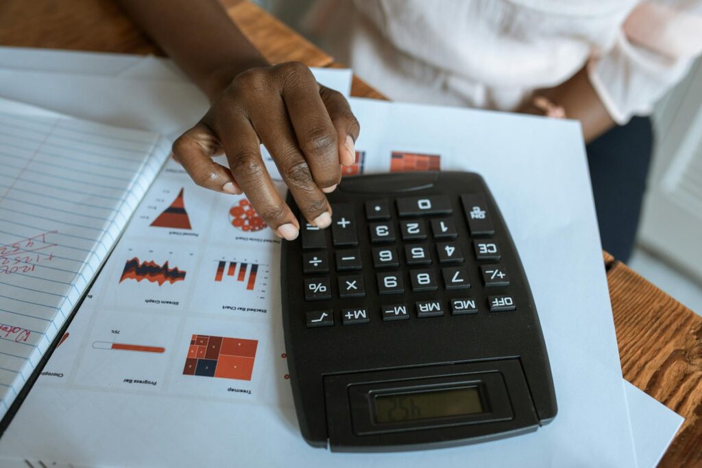Calculator and investment paperwork on a desk beside a notebook used to compare fees