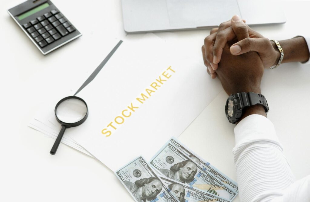 Investment statements and a calculator on a tidy desk beside a notebook