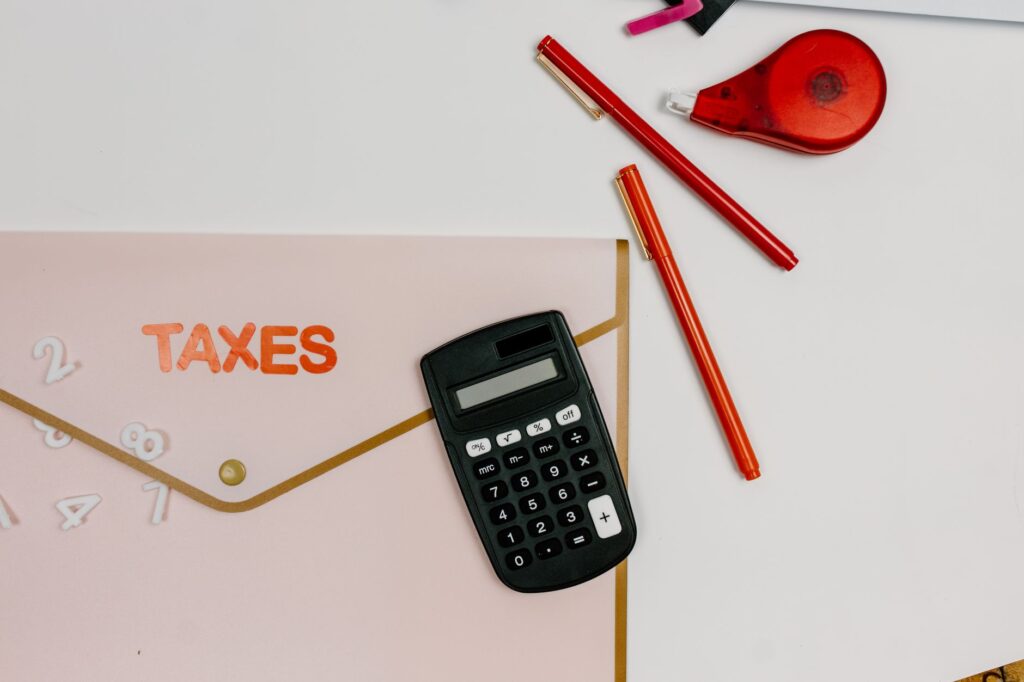 A desk with a calculator, notebook, retirement account paperwork, and a pen.