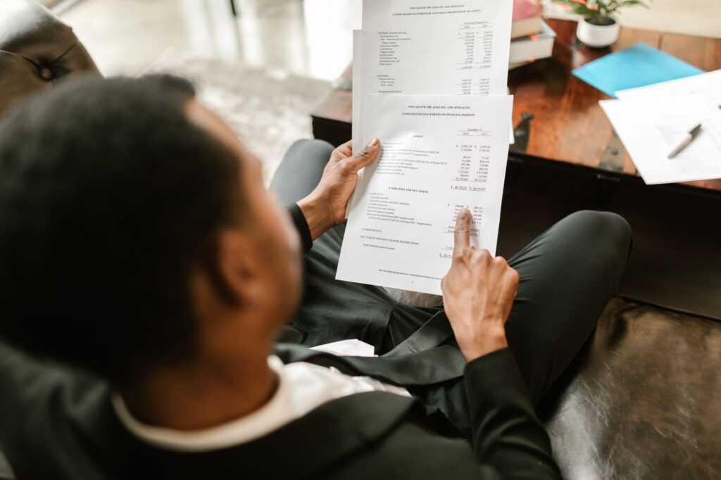 A person comparing numbers on printed investment account statements