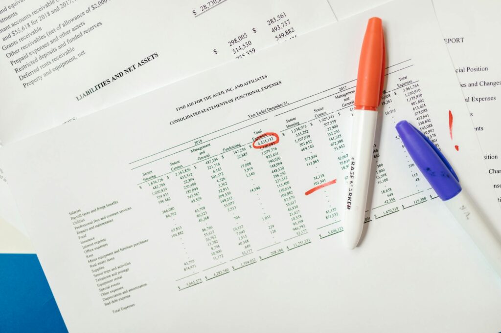 Calculator and printed investment statements with numbers marked for review