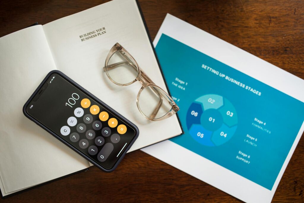 A brokerage account statement, calculator, and notebook laid out on a desk for review