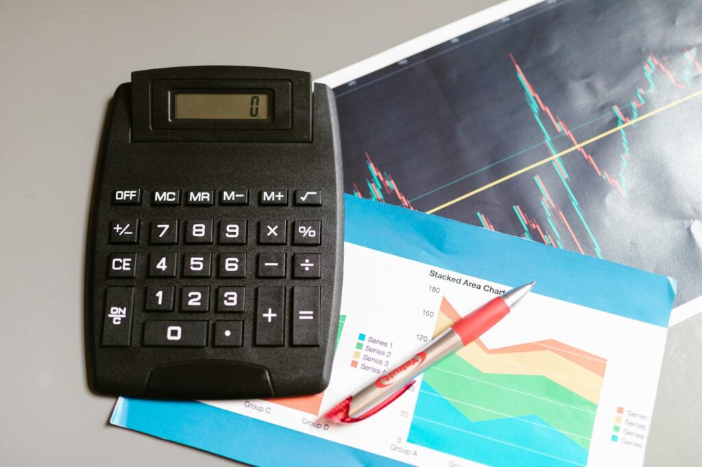 A person reviewing a fund report with a calculator and household bills on the table.