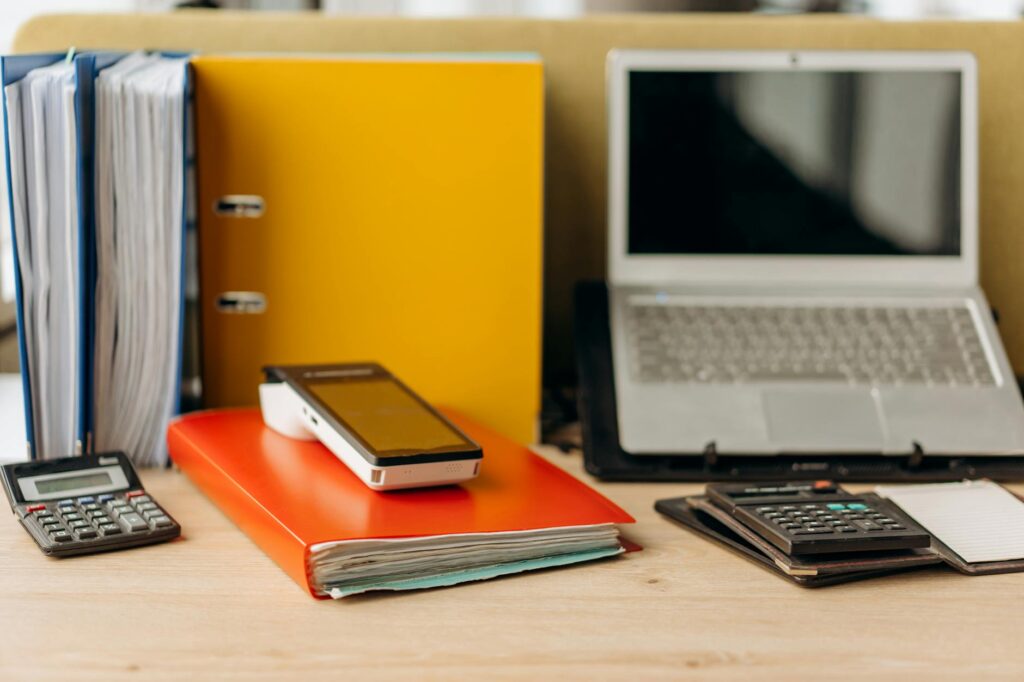 Printed investment documents, calculator, and notebook on a tidy desk