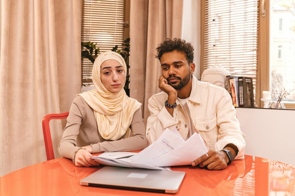 A couple reviewing bills and savings notes at a kitchen table.