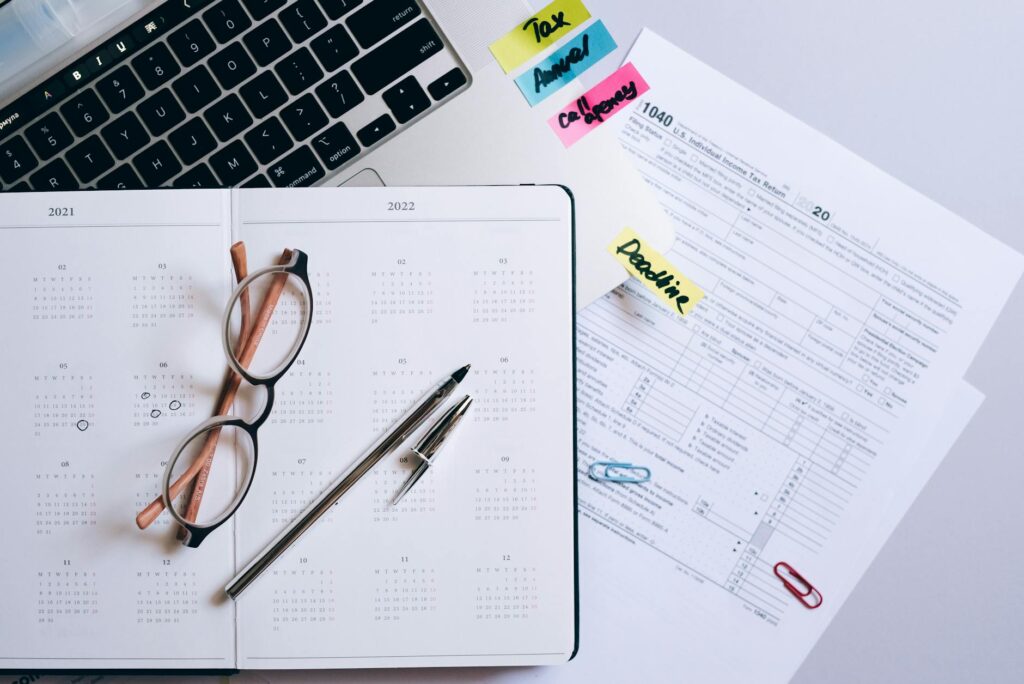 Notebook, laptop, and monthly calendar used for household financial planning