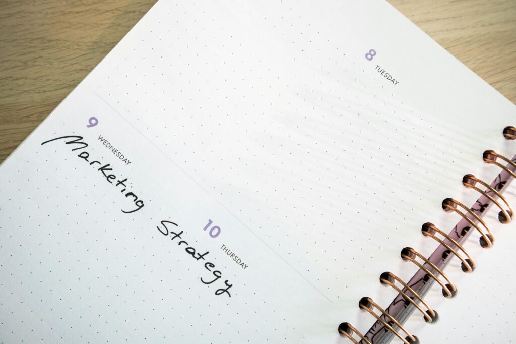 A person writing stock, bond, and cash allocation targets on a notepad next to account paperwork.