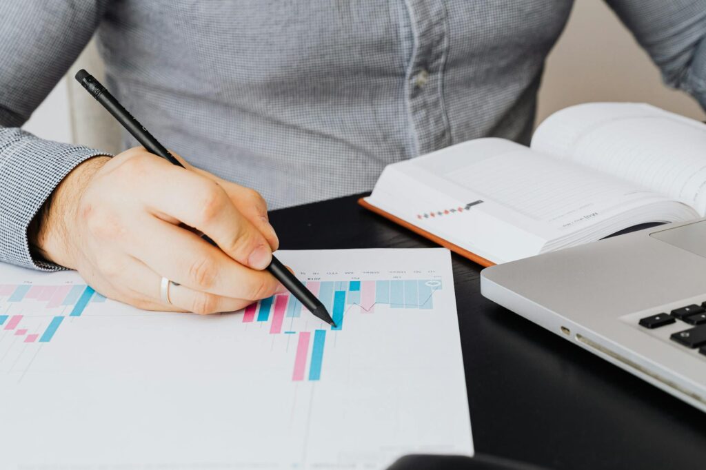 A spreadsheet printout and pen on a tidy workspace used for reviewing household investments.
