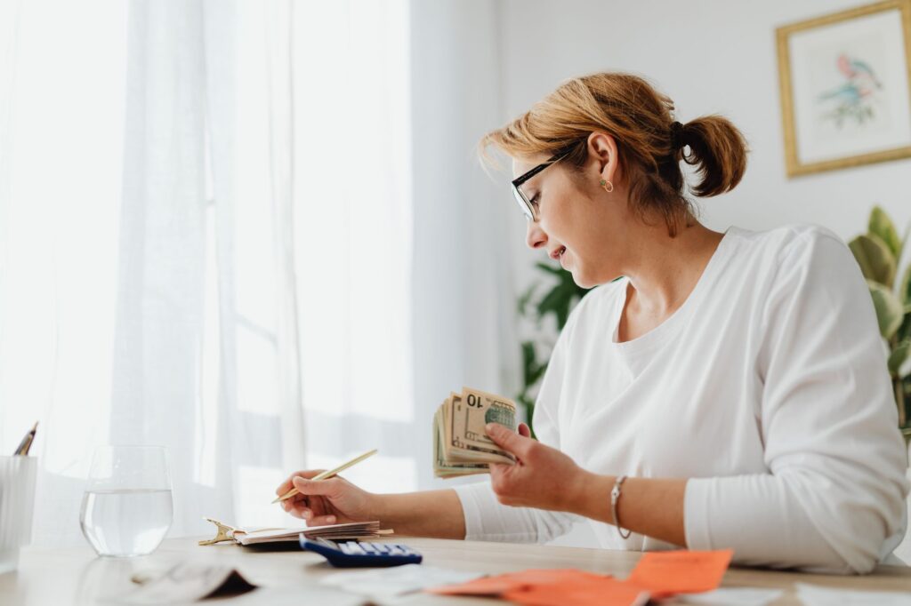 A tidy desk with a calculator, calendar, notebook, and papers showing household savings goals.