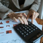 A desk with a calculator, retirement notes, and investment statements