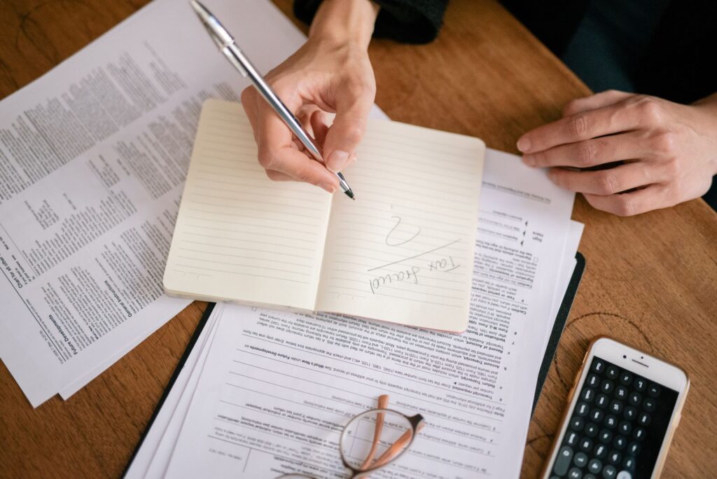 A person at a desk reviewing printed fund documents with a notebook and calculator.