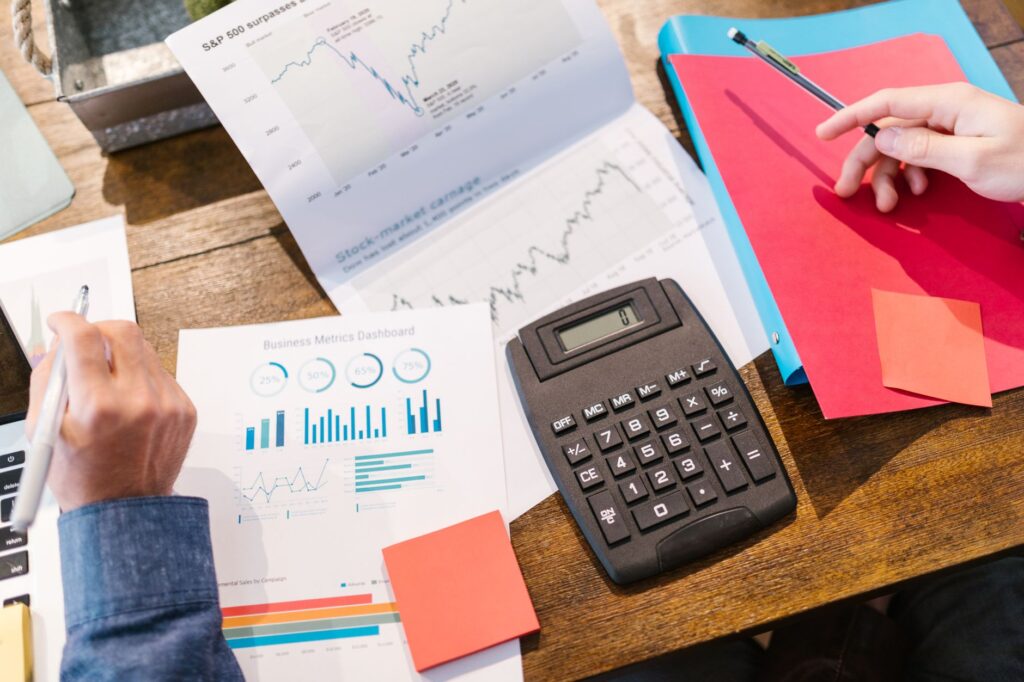 A person reviewing a printed fund fact sheet with a calculator and notes on a desk