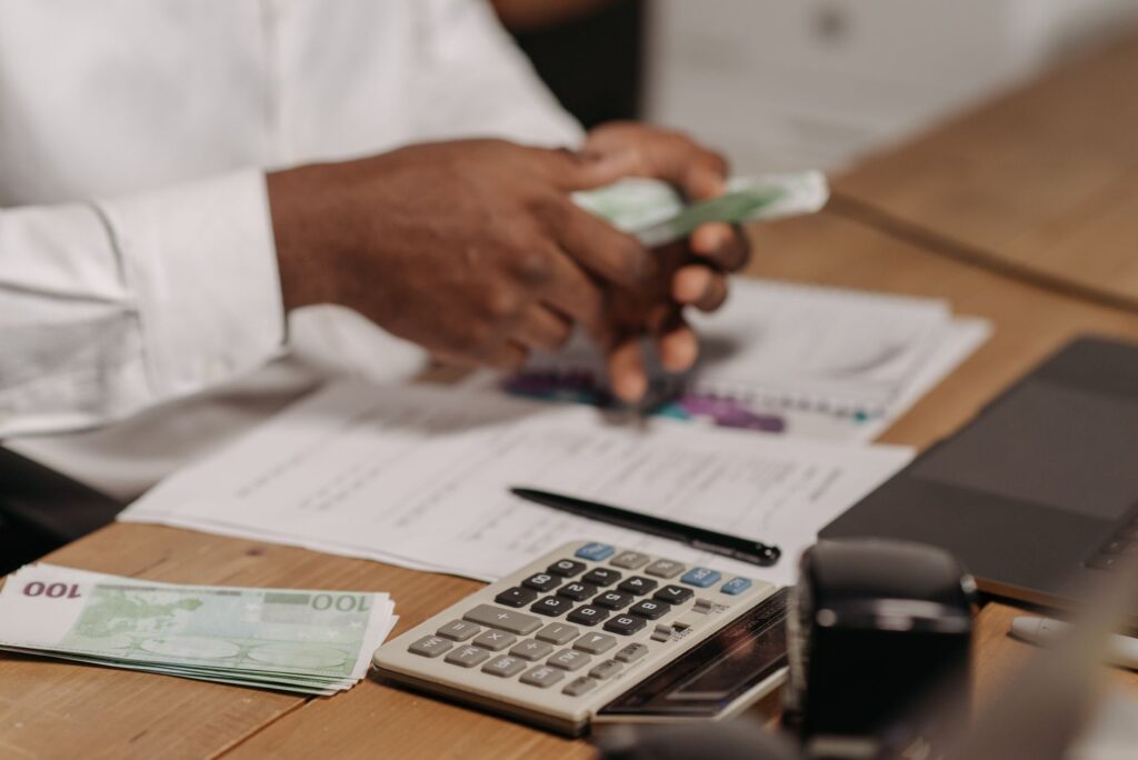 A desk with investment paperwork, a notebook, and a calculator arranged for research