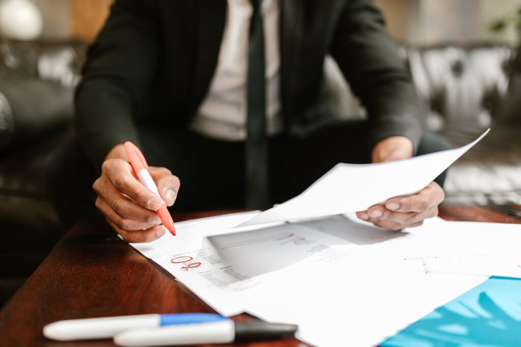 A desk with fund documents, a calculator, and handwritten notes comparing investment costs.