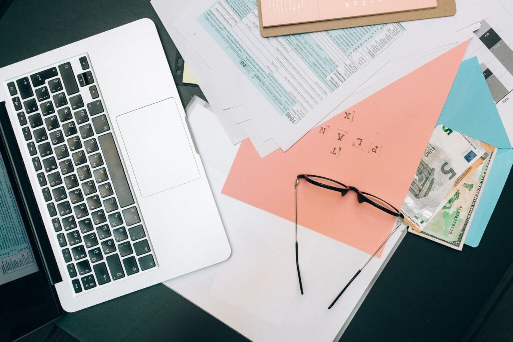 A home office desk with a laptop, calendar, and neatly arranged financial paperwork.